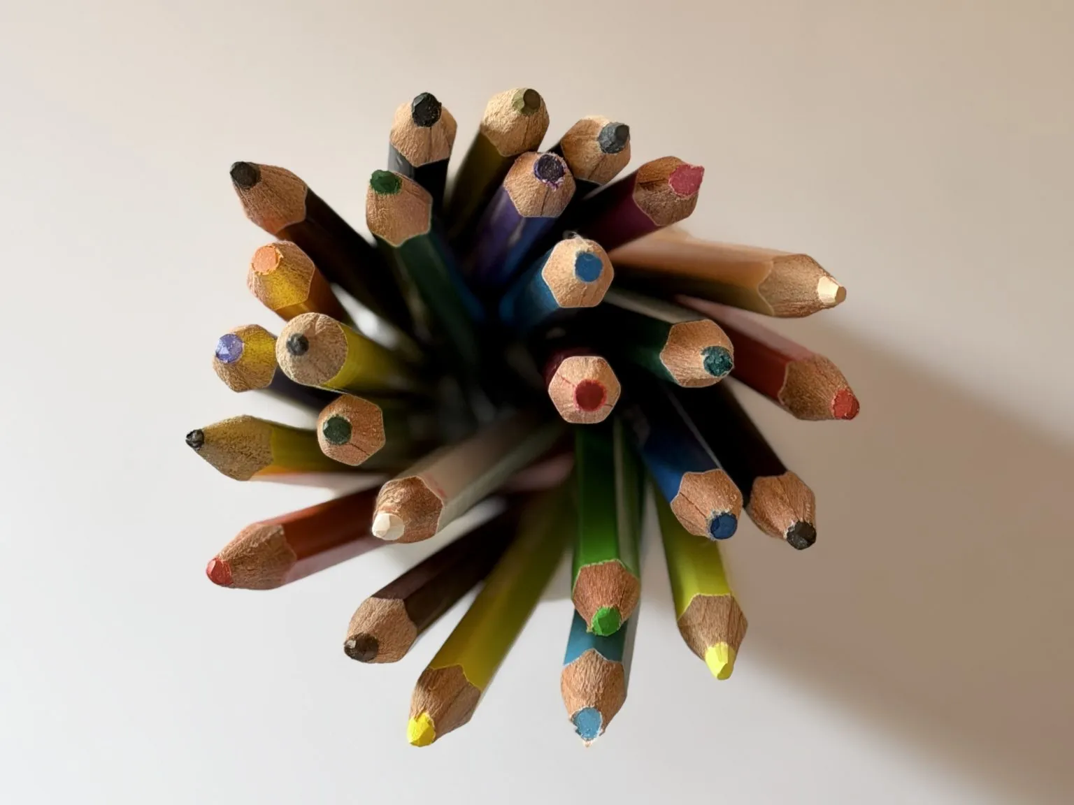 Sharpened colored pencils form a loose cluster viewed from above.