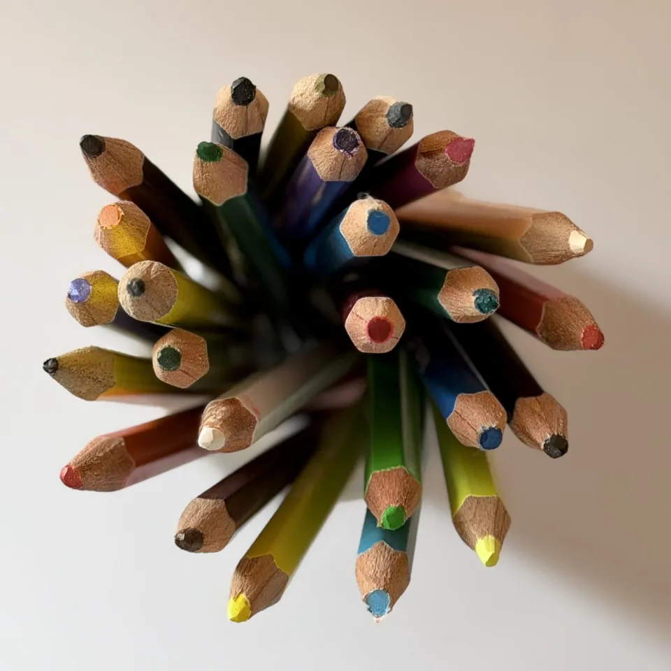 Sharpened colored pencils form a loose cluster viewed from above.
