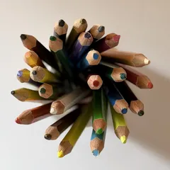 Sharpened colored pencils form a loose cluster viewed from above.