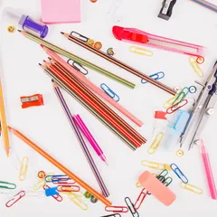 Bright pencils, pens, paper clips, a compass and rulers lie on a white surface.